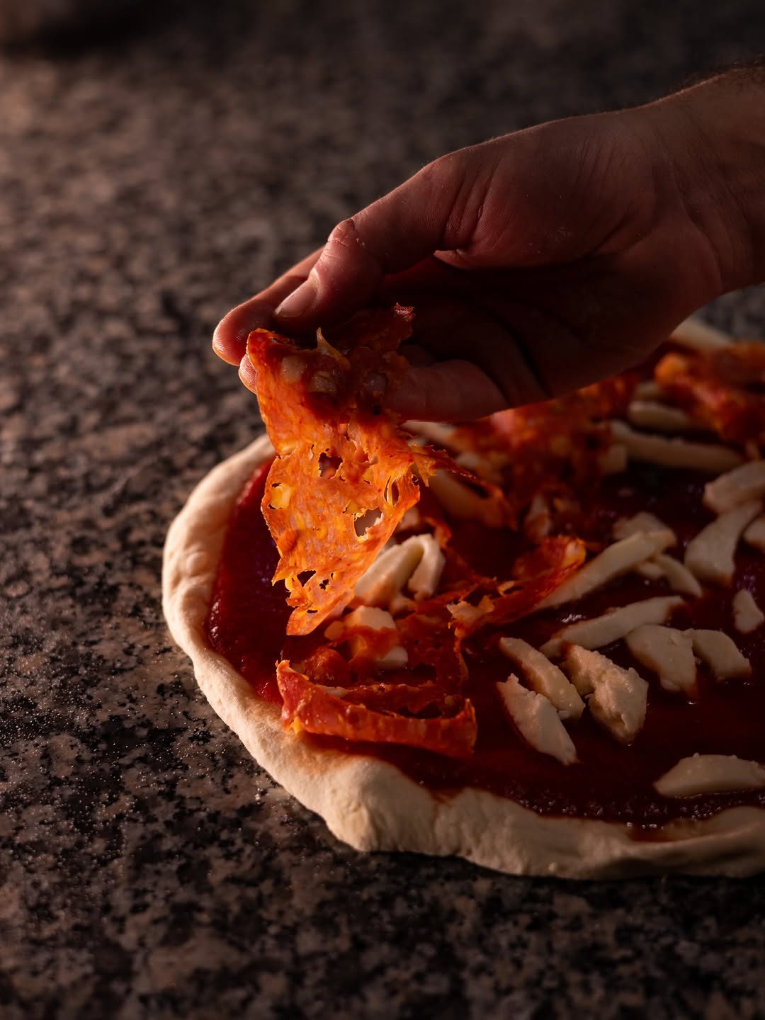 Pizza con pomodoro, mozzarella e salame piccante prima del forno